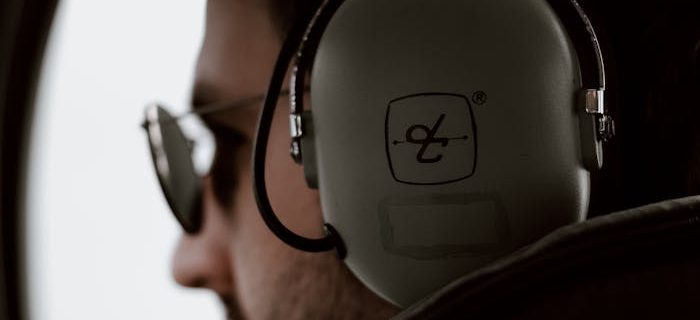 Profile of an aviator in cockpit wearing headset and sunglasses, emphasizing aviation lifestyle.